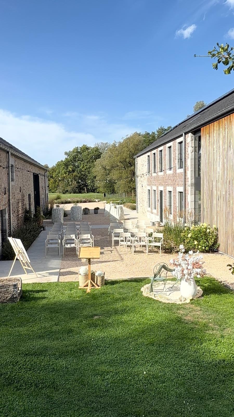 Rangées de chaises blanches installées pour une cérémonie, devant les bâtiments du domaine