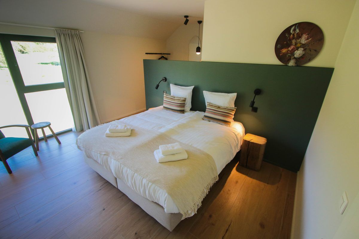 Chambre à la tête de lit peinte en vert sapin, porte-fenêtre sur la verdure
