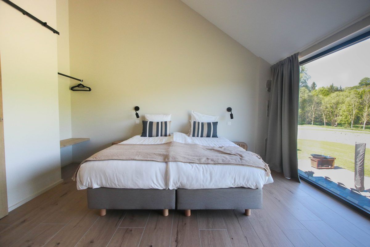 Chambre 9 : lit double face à une grande baie sur la prairie