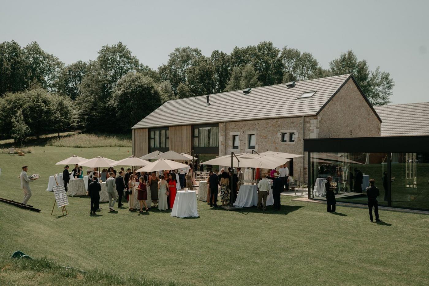 Fête dans le jardin, invités et parasols devant la Maison