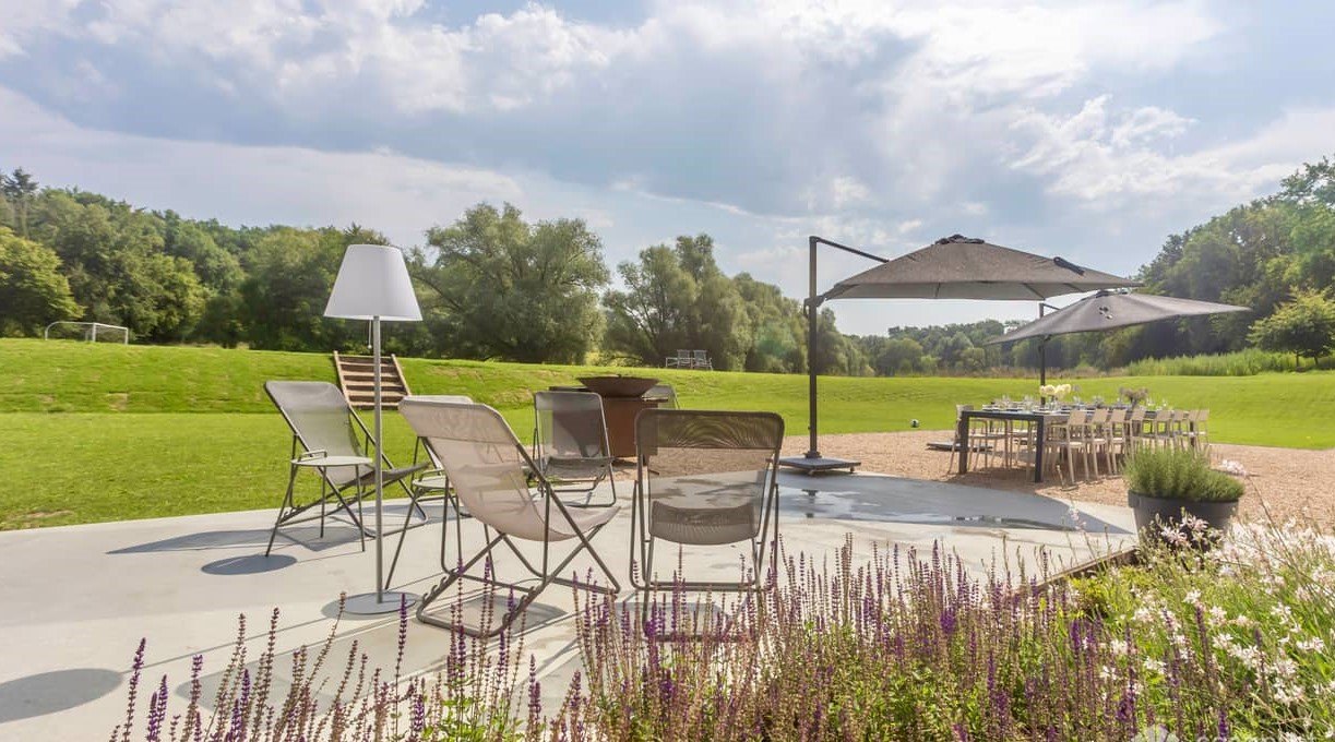 Salon de jardin et parasol sur la terrasse de la Maison, face à la prairie