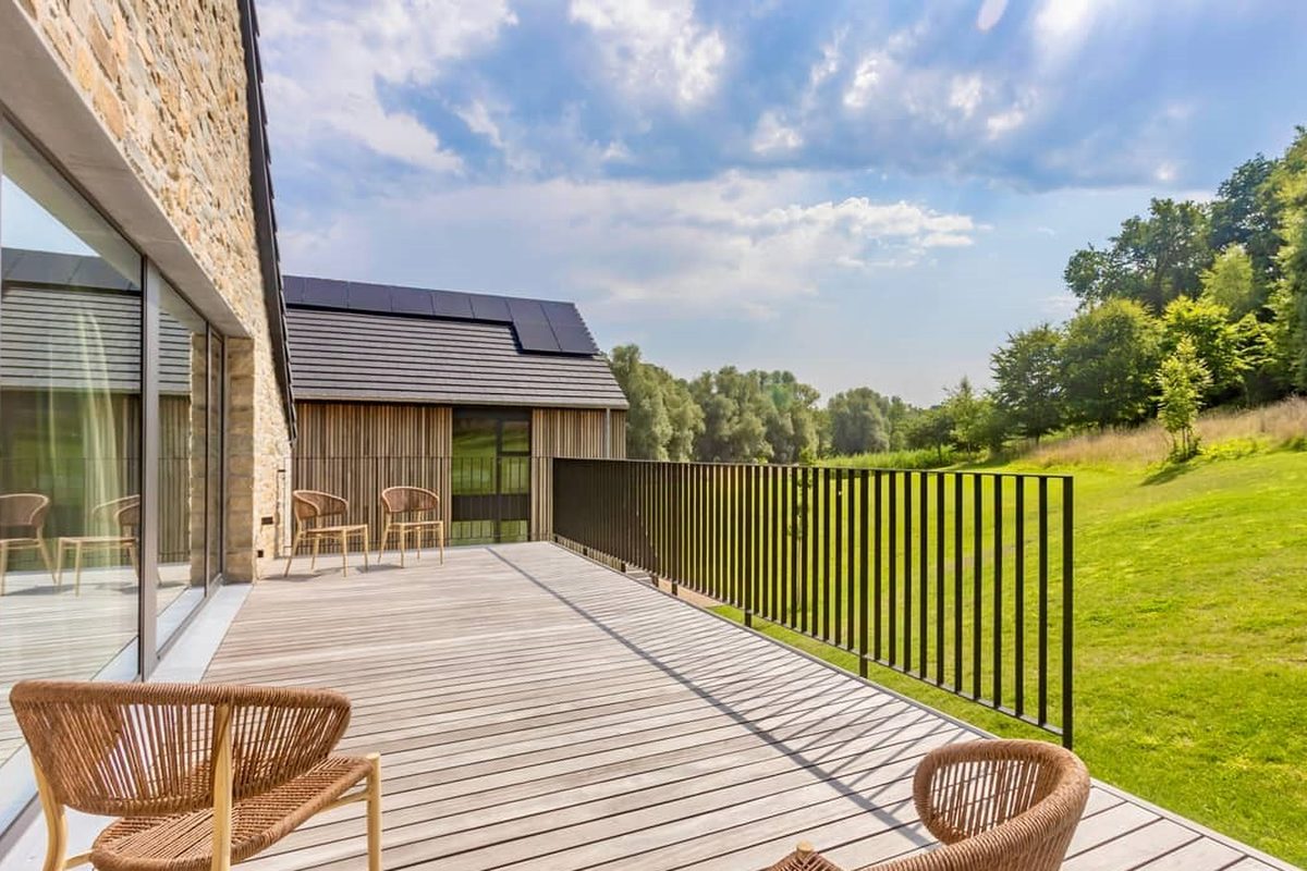 Terrasse en bois du Moulin, fauteuils en rotin face à la prairie