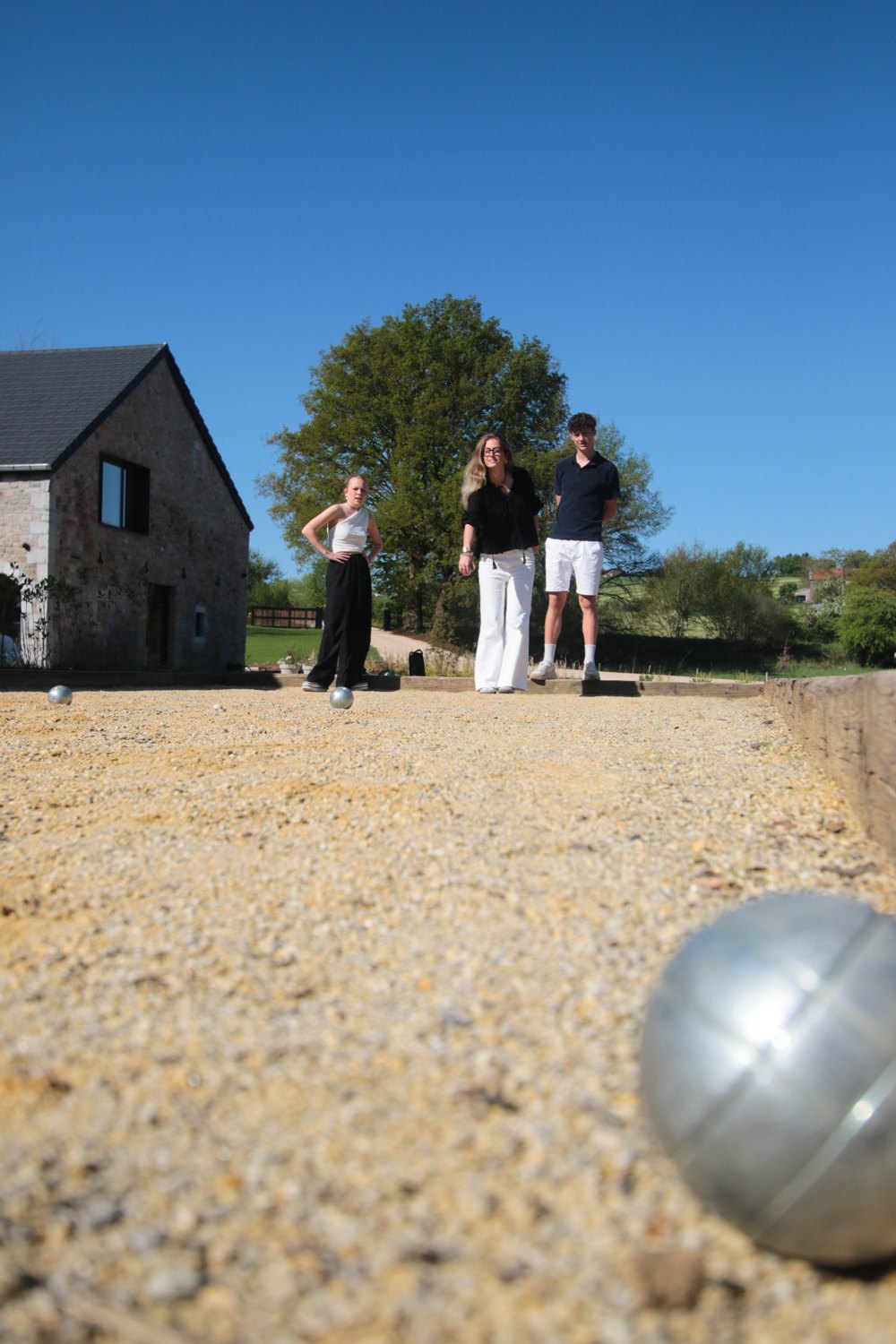 Boule de pétanque sur le terrain, joueurs en arrière-plan