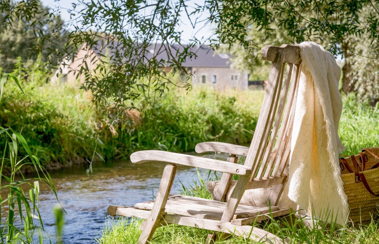 Transat et panier de pique-nique posés dans l’herbe au bord de la rivière